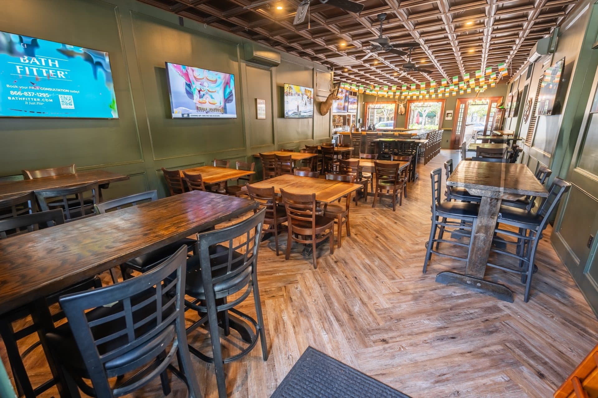 Spacious dining room at O'Brion's Pub & Grille in Mount Pleasant SC with wood tables, high-tops, green walls, and flat-screen TVs