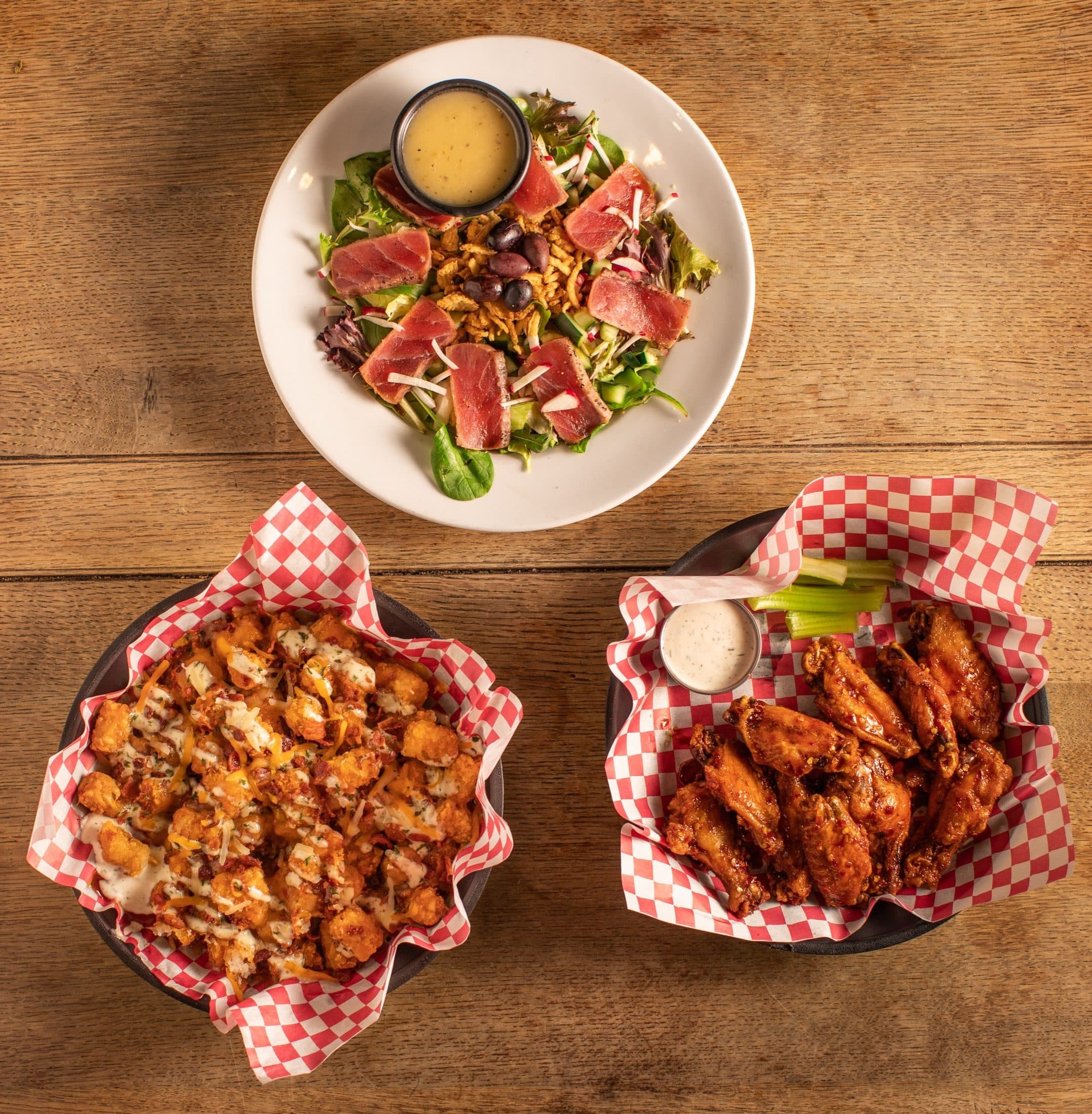 Shareables & Salads at O'Brion's Pub & Grille — Perfect for Groups in Mount Pleasant SC Assorted dishes including wings, loaded tots, and salad spread across the table at O'Brion's Pub & Grille